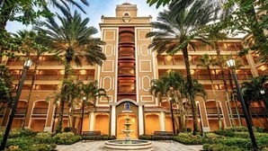 Ein mehrstöckiges Hotel mit Innenhof, Palmen und einem Brunnen.