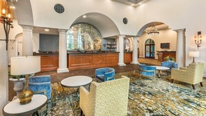 Eine geräumige Lobby mit einer Rezeption, einer Sitzecke und einem großen Bogenfenster.
