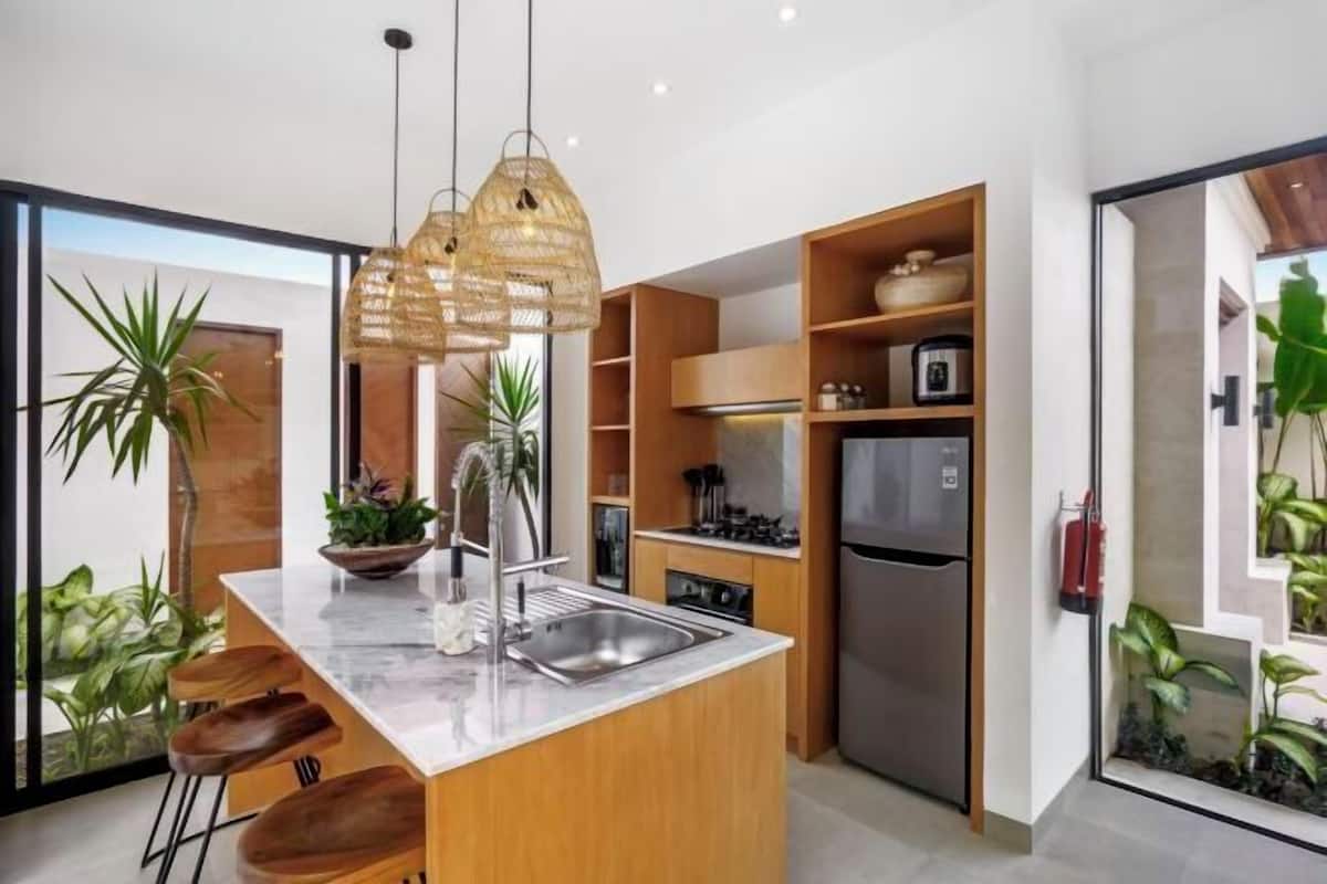 A modern kitchen with a central island, wooden cabinetry, stainless steel appliances, and pendant lighting.