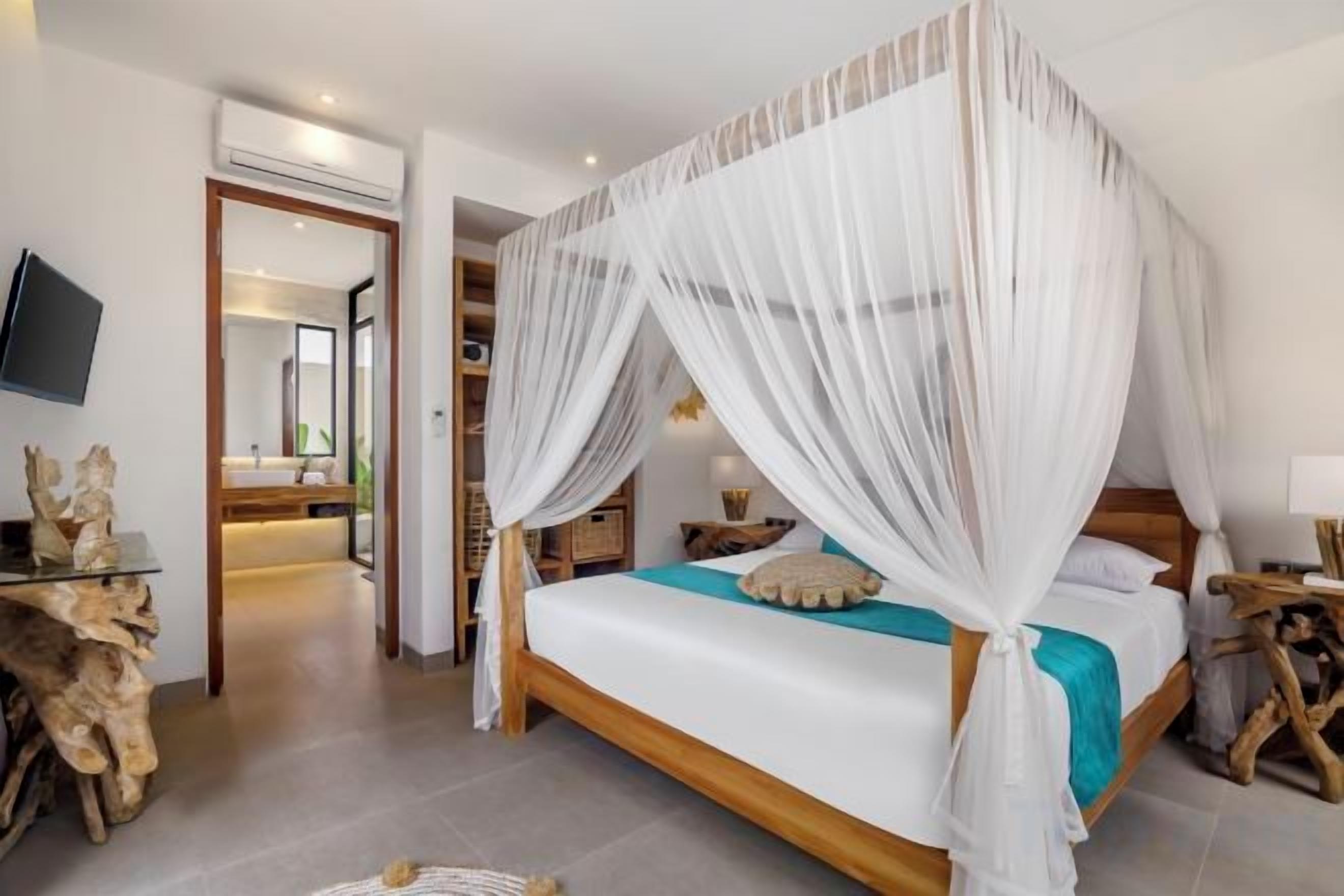 A bedroom with a canopy bed, a wooden headboard, a bedside table, and a mirror.