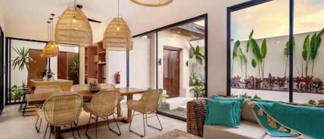 A modern interior with a dining area, sofa, and large windows.