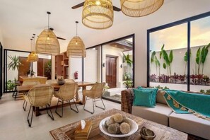 A modern interior with a dining area, sofa, and large windows. - Villa Crystal Lagoon by BaliSuperHost (Bali)