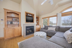A living room with a fireplace, a television, a sofa, and a bookshelf. - 1825 - Off The Clock - Dog-Friendly Corolla Getaway w/ Pool (Corolla)