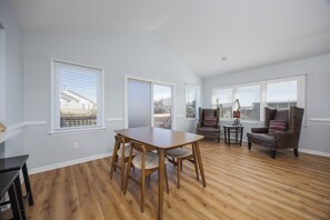 A spacious living room with a wooden dining table and chairs, a leather armchair, and a small side table. - 5371 - Masion Azur - Kill Devil Hills Coastal Escape Near Beach (Kill Devil Hills)