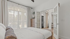 Un dormitori amb un llit gran, una petarrera i una porta que condueix a una altra habitació.