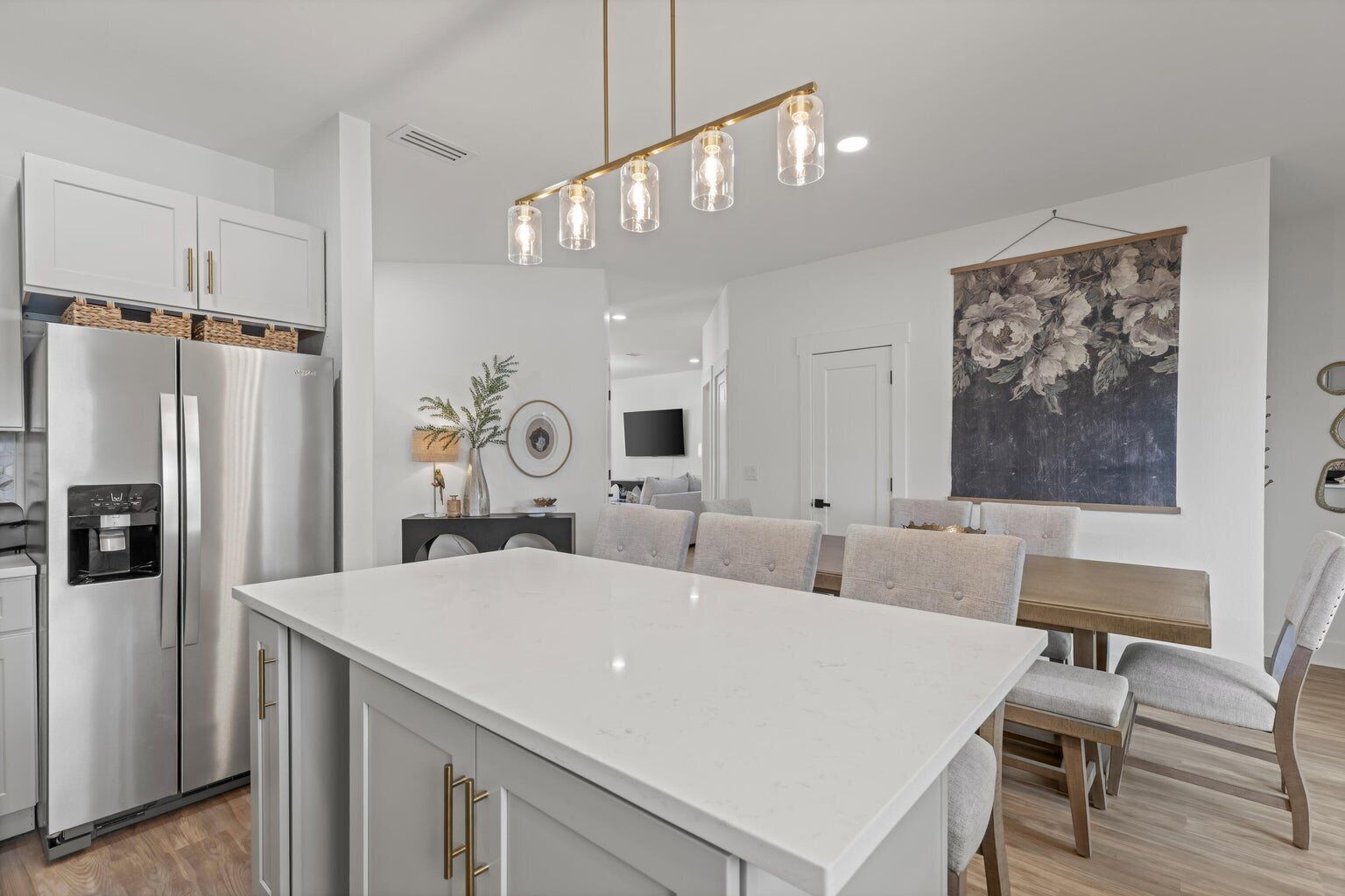 A modern kitchen with a large island, stainless steel appliances, and a dining area with a table and chairs.