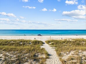 Ein Strand mit einem klaren Weg zum Wasser, einigen Personen und einem Zelt.