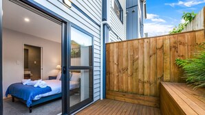 A modern bedroom with a large sliding glass door leading to a balcony. - Modern Townhouse with Parking near Cornwall Park (Auckland South)