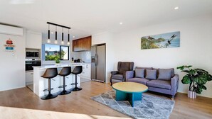 A modern kitchen with a central island, bar stools, a sofa, and a coffee table. - Modern Townhouse with Parking near Cornwall Park (Auckland South)