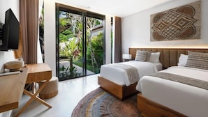 A modern hotel room with a large sliding glass door to a garden, a wooden desk, two beds, and a wall-mounted artwork. - Villa Aman by BaliSuperHost (Bali)