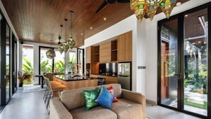 A modern living room with a sofa, a dining area, and a kitchen. - Villa Aman by BaliSuperHost (Bali)