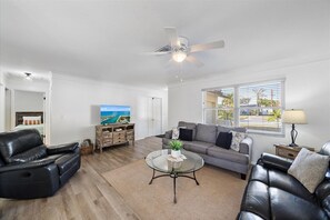 A modern living room with a leather sofa, a glass coffee table, and a TV on a wooden cabinet. - Private Pool + Kid's Play Area | Diamond's Legacy (Sarasota)