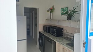 Een kleine keuken met een wasmachine, een magnetron en een spoelbak.