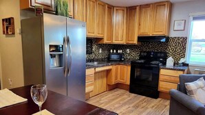 A kitchen with wooden cabinets, a stainless steel refrigerator, a microwave, and a stove. - Silver Creek Accessible Studio (Helena)