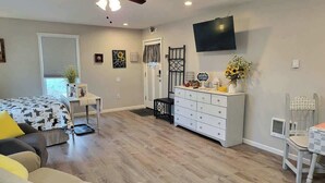 A bedroom with a bed, dresser, TV, and a small table with a plant. - Silver Creek Accessible Studio (Helena)
