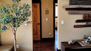 Un pasillo con una puerta de madera, un estante empotrado con decoración rústica y una planta en maceta.