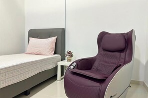 A room with a bed, a small bedside table, and a massage chair. - Setia Tri-Suite(3) by Homey Planet (Bayan Lepas)