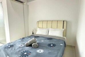A bed with a headboard, pillows, and a rolled towel. - Setia Tri-Suite(3) by Homey Planet (Bayan Lepas)