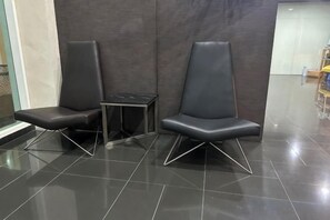 Two black chairs with metal legs, a small table, and a dark tiled floor. - Setia Tri-Suite(3) by Homey Planet (Bayan Lepas)
