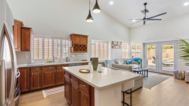 A spacious kitchen with wooden cabinets, a large island, and a ceiling fan. - Ahwatukee Adventures Family Home + Pool (Phoenix)