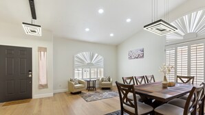 A spacious dining area with a wooden table and chairs, a small round table with chairs, and a decorative rug. - Ahwatukee Adventures Family Home + Pool (Phoenix)