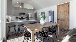 Una cocina moderna con armarios grises, una mesa de comedor de madera y sillas negras.