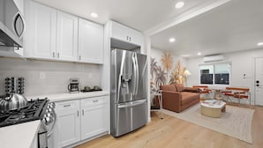 A modern kitchen with white cabinets, a stainless steel refrigerator, and a gas stove. - Designer 2BR in Prime Location w/ Outdoor Dining! (San Diego)