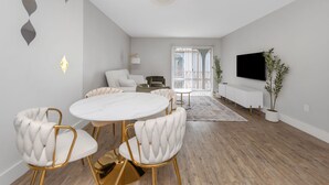 Una sala de estar moderna con una mesa redonda de comedor, sofás blancos y un televisor de pantalla plana.
