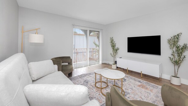 Una sala de estar moderna con un sofá blanco, una mesa de centro, un televisor y una planta en maceta.