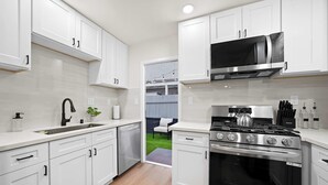 Una cocina moderna con armarios blancos, estufa de acero inoxidable y microondas.