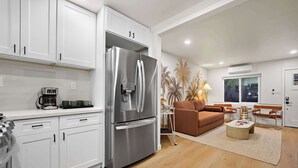 Una cocina moderna con armarios blancos, un refrigerador de acero inoxidable y una cafetera.