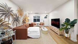 Una sala de estar moderna con un sofá marrón, una mesa de centro, un televisor y un comedor con sillas y una mesa.