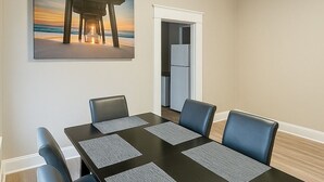 A conference room with a long table, six chairs, and a painting of a beach scene. - Stylish 2BR Near ECU Health, ECU & Downtown • Fast WiFi (Greenville)