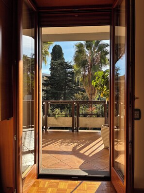 A view from inside a room to a balcony with a tiled floor, a railing, and various plants. - Gianicolo Belvedere House (Roma)