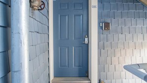 A blue door with a number plate, a metal pipe, and a vent on the wall. - Harbour Club A5 (Ocean City)