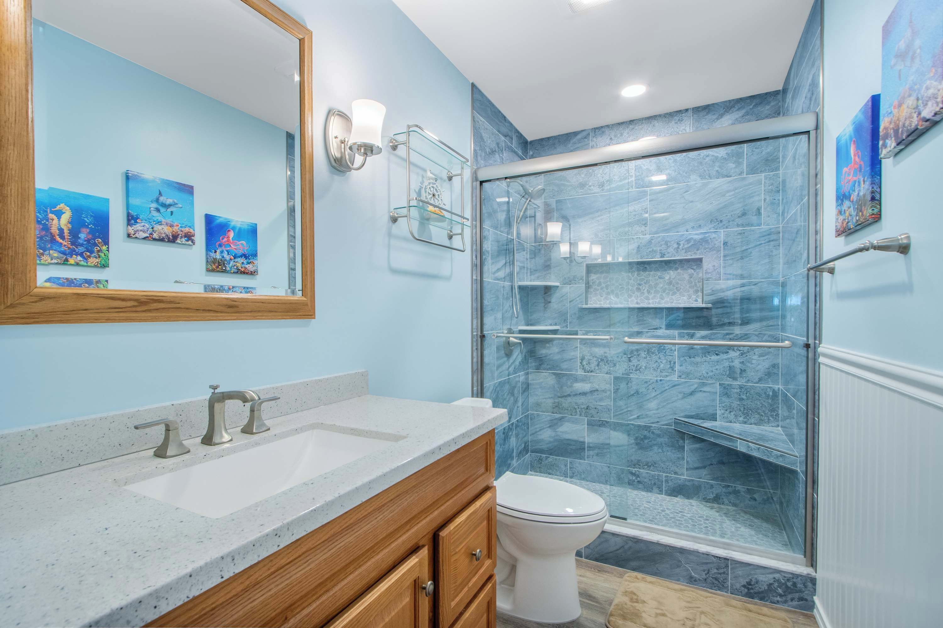 A bathroom with a glass-enclosed shower, a white sink, and a wooden vanity.