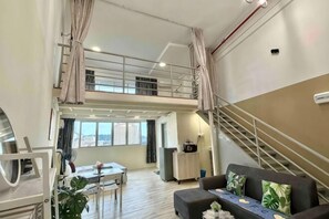 A spacious living area with a dining table, sofa, and a staircase leading to an upper level. - The CEO Suite9 By Homey Planet (Bayan Lepas)