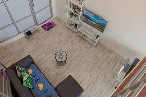 A room with a sofa, a coffee table, a bookshelf, a painting, and a staircase. - The CEO Suite9 By Homey Planet (Bayan Lepas)