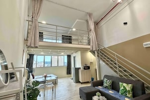 Amplia sala de estar con mesa de comedor, sofá y una escalera que conecta dos niveles.