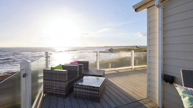 Una terraza con mobiliario de mimbre y vista al océano.