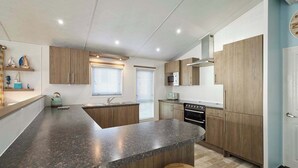 Una cocina moderna con armarios de madera, encimera de granito, horno empotrado y microondas.
