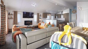 Una sala de estar moderna con un sofá, televisor y un comedor con mesa y sillas.