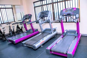 Three treadmills in a gym with a city view through the window. - Premium furnished studio in Nairobi with rooftop fitness room (Nairobi)