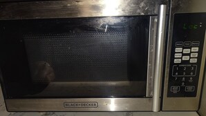 Eine BLACK+DECKER Mikrowelle mit digitaler Bedieneinheit auf einer Marmorarbeitsplatte.