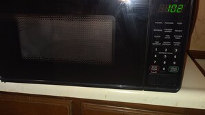 Eine schwarze Mikrowelle mit digitalem Display auf einer weißen Arbeitsplatte.