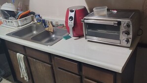 Eine Küche mit Spüle, einem roten Gerät, einem Toaster und Holzschränken.