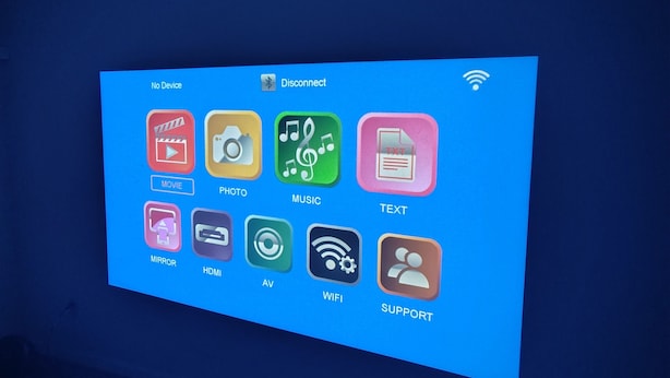 Eine wandmontierte Anzeige mit verschiedenen App-Symbolen, darunter „FILM“, „FOTO“, „MUSIK“, „TEXT“, „SPIEGEL“, „HDMI“, „AV“, „WLAN“ und „SUPPORT“.