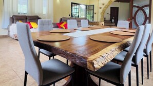 Un comedor amplio con una gran mesa de madera, sillas grises tapizadas y un alto techo con vigas a la vista.