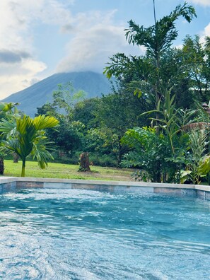 A swimming pool with a view of a mountain and lush greenery. - Arenal: A Tropical Home (La Fortuna)
