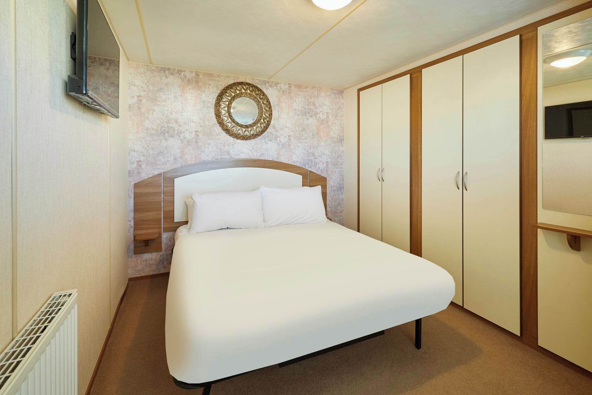 A bedroom with a bed, a wardrobe, a mirror, and a radiator.
